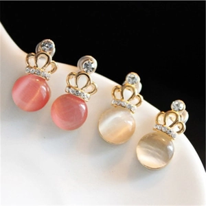 Close-up of elegant crown earrings with pink and beige cat eye stones and rhinestones
