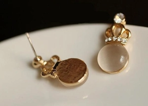 Detailed macro view of gold plated crown stud earrings with rhinestones and opal stone