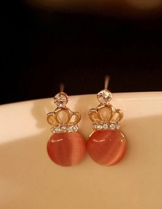 Detail of gold crown earrings with sparkling rhinestones and pink cat eye stone beads