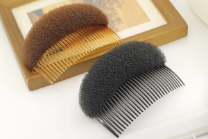 Hair volume padding comb shown in black and brown on a minimalist wooden background
