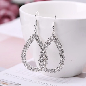 Elegante silberne Tropfenohrringe mit Strasssteinen an einer weißen Keramiktasse hängend