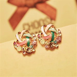 Macro shot of colorful enamel knot stud earrings with pink and green sparkling crystals