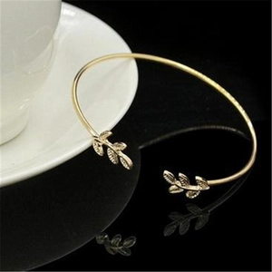 Detailed close-up of golden leaf-shaped ends on an adjustable open cuff bracelet