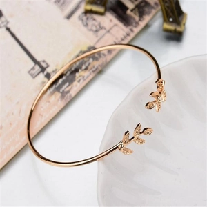 Close-up of rose gold leaf bracelet on a decorative ceramic tray with French scenery