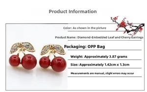Macro view of cherry stud earrings featuring gold leaves with sparkling white rhinestones