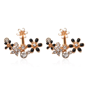 Detail of floral earrings with gold plating, rhinestones, and black and white petals
