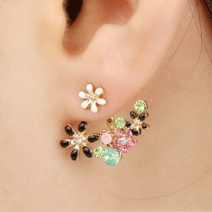 Close-up of model wearing floral stud earrings with multi-color crystals and gold base