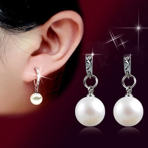 Detail view of pearl drop earrings featuring silver textured hoops and large white pearls