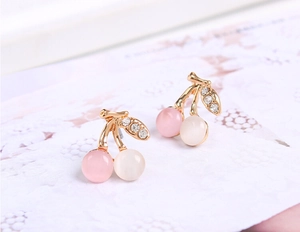 Détail macro de boucles d'oreilles cerise avec perles d'opale et feuilles en cristal doré