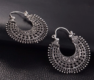Détail macro de boucles d'oreilles créoles vintage avec motifs floraux bohèmes argentés