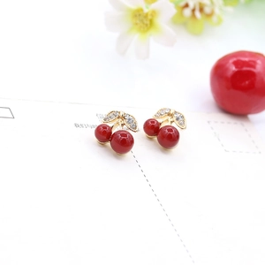 Detailed close-up of cherry stud earrings with red glossy fruit and crystal leaves