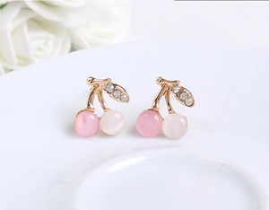 Détail macro de boucles d'oreilles cerises avec opales roses et feuilles en strass