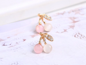 Détail des boucles d'oreilles cerises avec pierres œil de chat roses et diamants