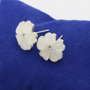 Detail of flower earrings with translucent white petals and center crystal stone