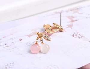 Vue macro des boucles d'oreilles cerises avec pierres d'opale rose blanc et cristaux