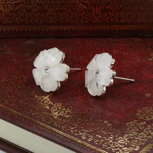 Detailed macro view of white floral stud earrings with clear center zircon accents