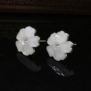 Macro detail of acrylic five-leaf flower earrings with glitter finish and rhinestone center