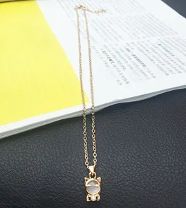 Nahaufnahme einer goldenen Katzen-Halskette mit weißem Opal-Anhänger und feiner Gliederkette