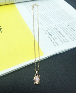 Detailansicht goldener Katzenanhänger mit rosa Katzenaugenstein und kleiner Perle