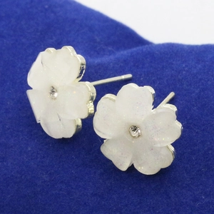Elegant white five-petal flower stud earrings with sparkling crystal center on blue velvet