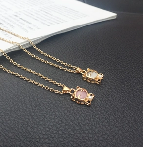 Detailansicht der rosa und weißen Katzen-Anhänger mit Opal und Perlen an Goldkette