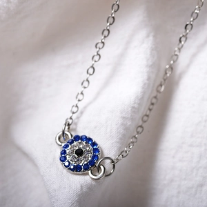 Nahaufnahme eines silbernen Evil Eye Fußkettchens mit blauen und weißen Zirkonia-Steinen
