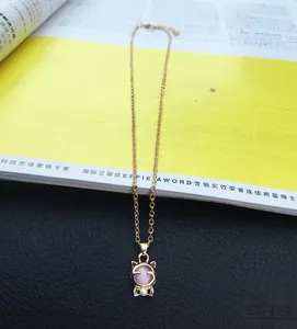 Makro-Detail der katzenförmigen Goldkette mit rosa Edelstein und kleiner Perlenverzierung