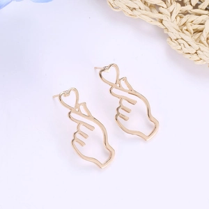 Detail of gold hollow heart gesture earrings on a clean white background with props