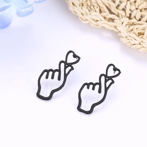 Detailed close-up of minimalist black heart-shaped gesture stud earrings on white background