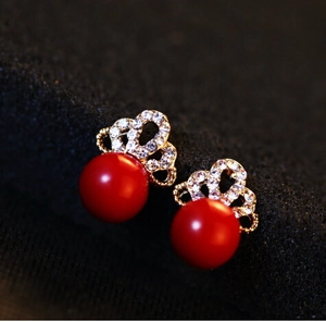 Detailansicht goldener Kronen-Ohrringe mit Diamanten und roten Perlen-Anhängern