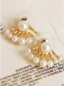 Détail macro de boucles d'oreilles dorées en éventail avec perles et fermoirs plastique