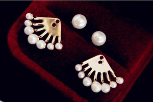 Détail de boucles d'oreilles en perles en forme d'éventail sur écrin en velours rouge