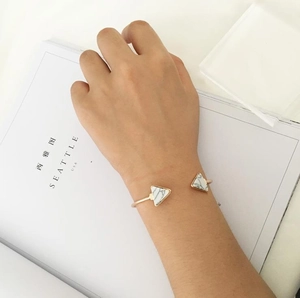 Detail of minimalist gold open bangle with white marble triangle inserts on a hand