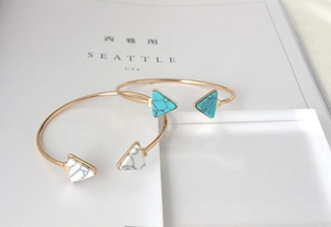 Detailed close-up of golden triangle cuffs featuring marble-textured turquoise inlay