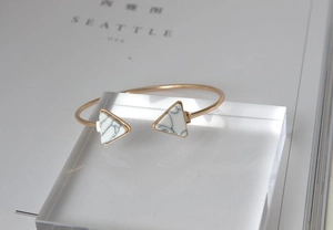 Close-up of golden triangle open bangle with white marble turquoise stone inlays