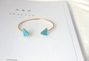 Detail of gold open cuff bracelet featuring triangular turquoise stones with black veins