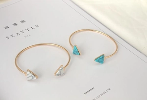 Detail of gold-plated alloy bracelets with marble and turquoise triangle accents