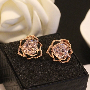 Vue détaillée de boucles d'oreilles roses creuses dorées avec un cristal de zircon brillant