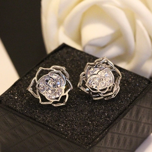 Gros plan sur des boucles d'oreilles roses argentées ajourées avec zircons et boîte noire