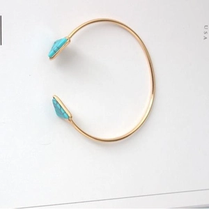 Minimalist golden open bracelet featuring triangular turquoise marble stones on white background