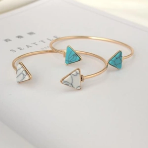 Golden open cuff bracelets with blue turquoise and white marble triangle stones on book