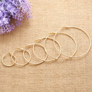 Detailed set of six pairs of polished golden hoop earrings in various sizes on linen