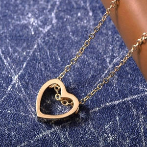 Macro shot of a polished gold hollow heart pendant on a fine chain over blue leather