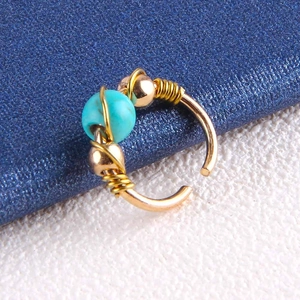 Detail of bohemian gold wire-wrapped nose ring with turquoise and small gold beads