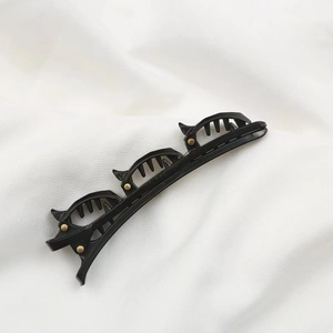 Black double-layer braided hair clip with small spring claws for styling on white fabric