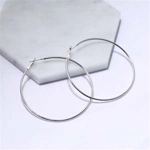 Minimalist silver hoop earrings with a polished metallic finish on white marble