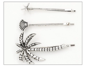 Detailed view of silver sea star, shell and palm tree hair clips set in a flat lay style