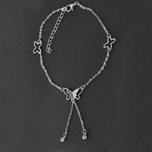 Bracelet de cheville papillon argenté avec glands en cristal sur fond texturé sombre