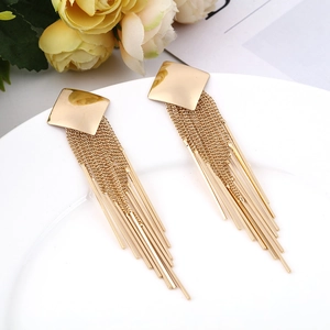 Detailed macro of long gold fringe earrings with square studs and metal tassels