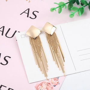 Detail of long gold metal tassel earrings with geometric square studs on a white card